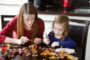 Mother and her kid making chestnuts creatures